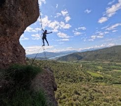 Participante cruzando el puente tibetano de la Vía Ferrata Roca Foradada en La Pobla de Segur, con vistas al embalse de Sant Antoni y al Prepirineo catalán