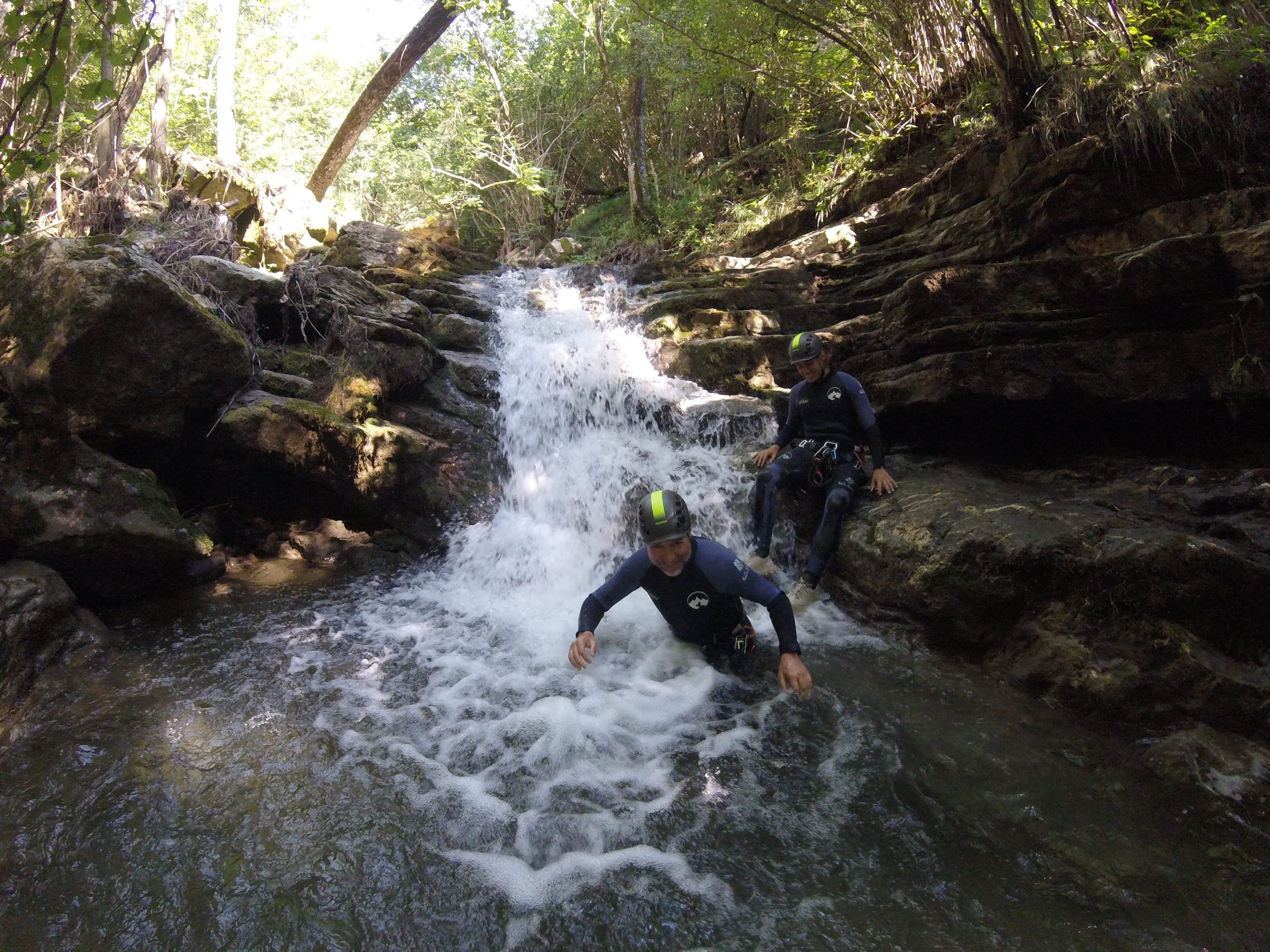 Participants de barranquisme baixant per una cascada envoltada de vegetació frondosa al Barranc del Pamano