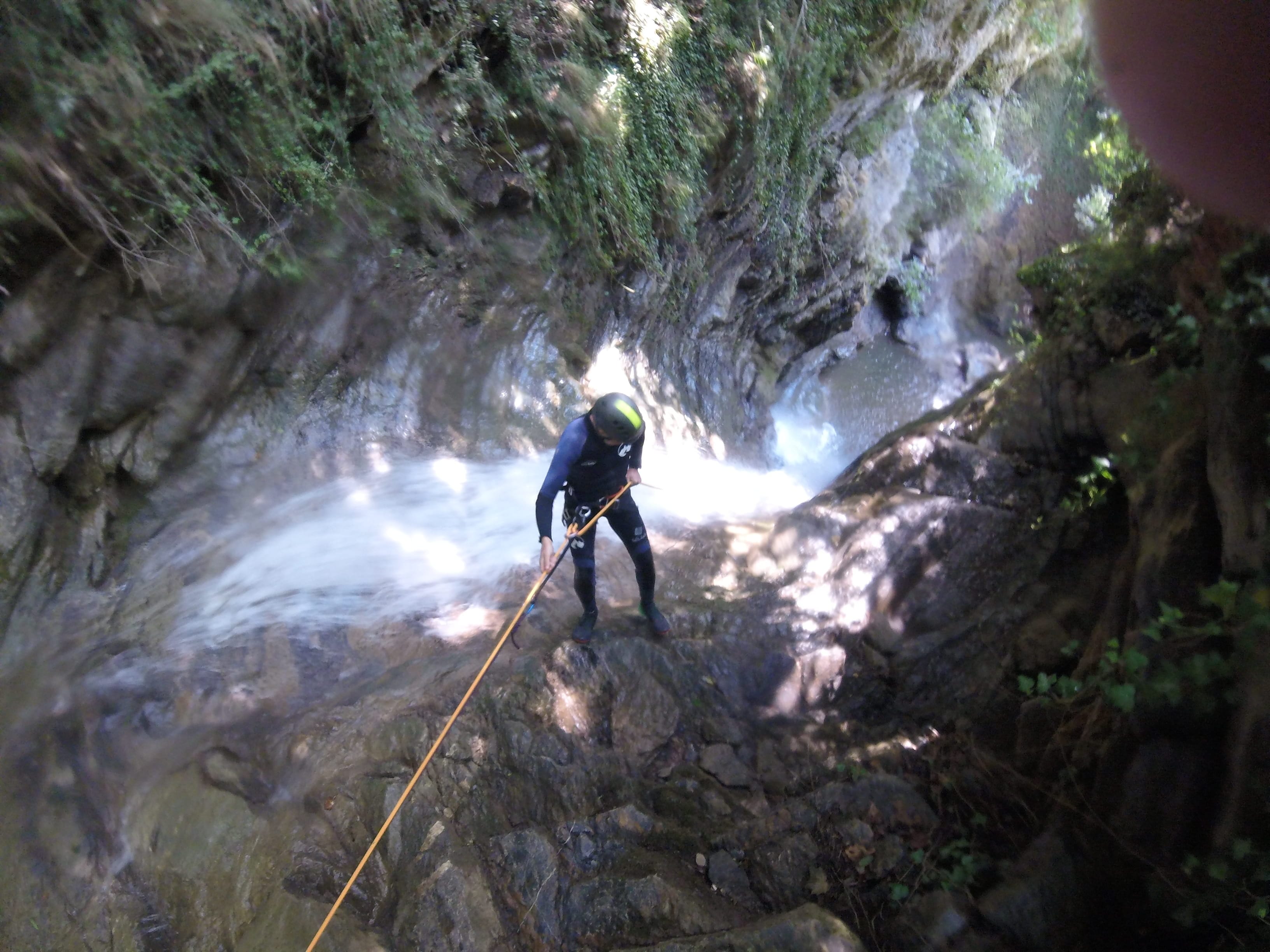 Participant de barranquisme baixant en ràpel al costat d’una cascada al bosc del Barranc del Pamano