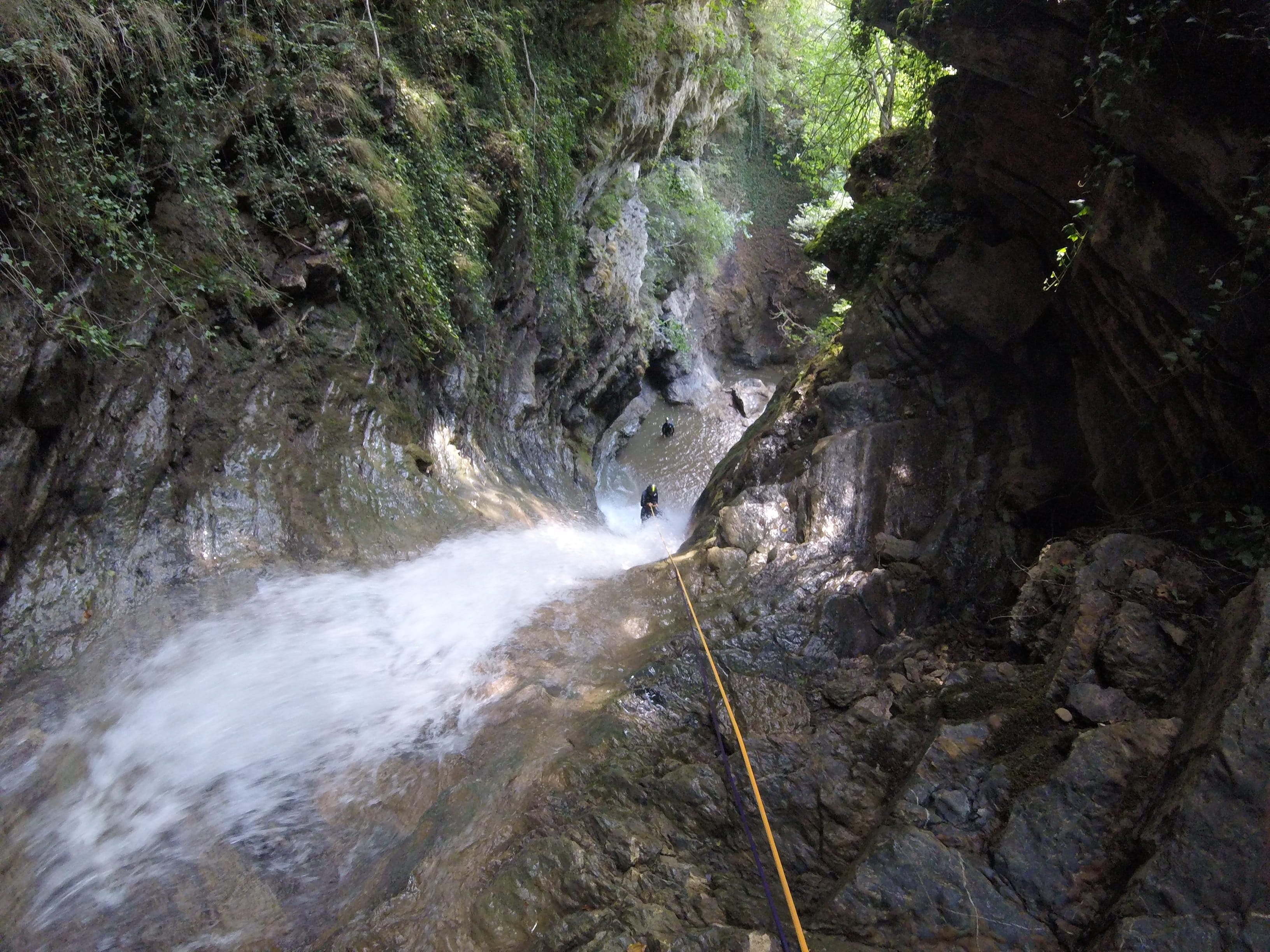 Vista d’una cascada amb una corda i participants de barranquisme al bosc del Barranc del Pamano