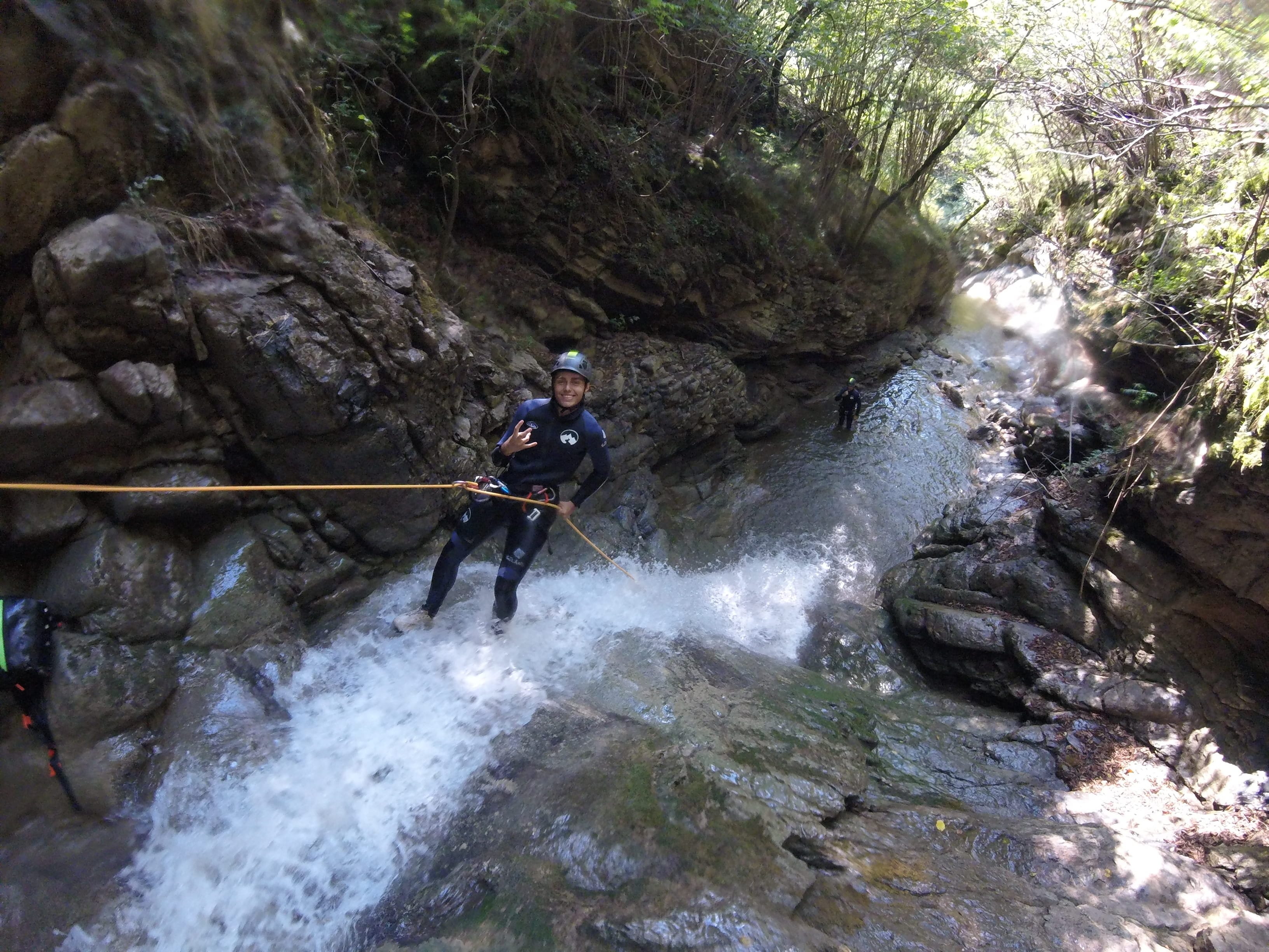 Participant de barranquisme baixant en ràpel per una cascada al bosc del Barranc del Pamano