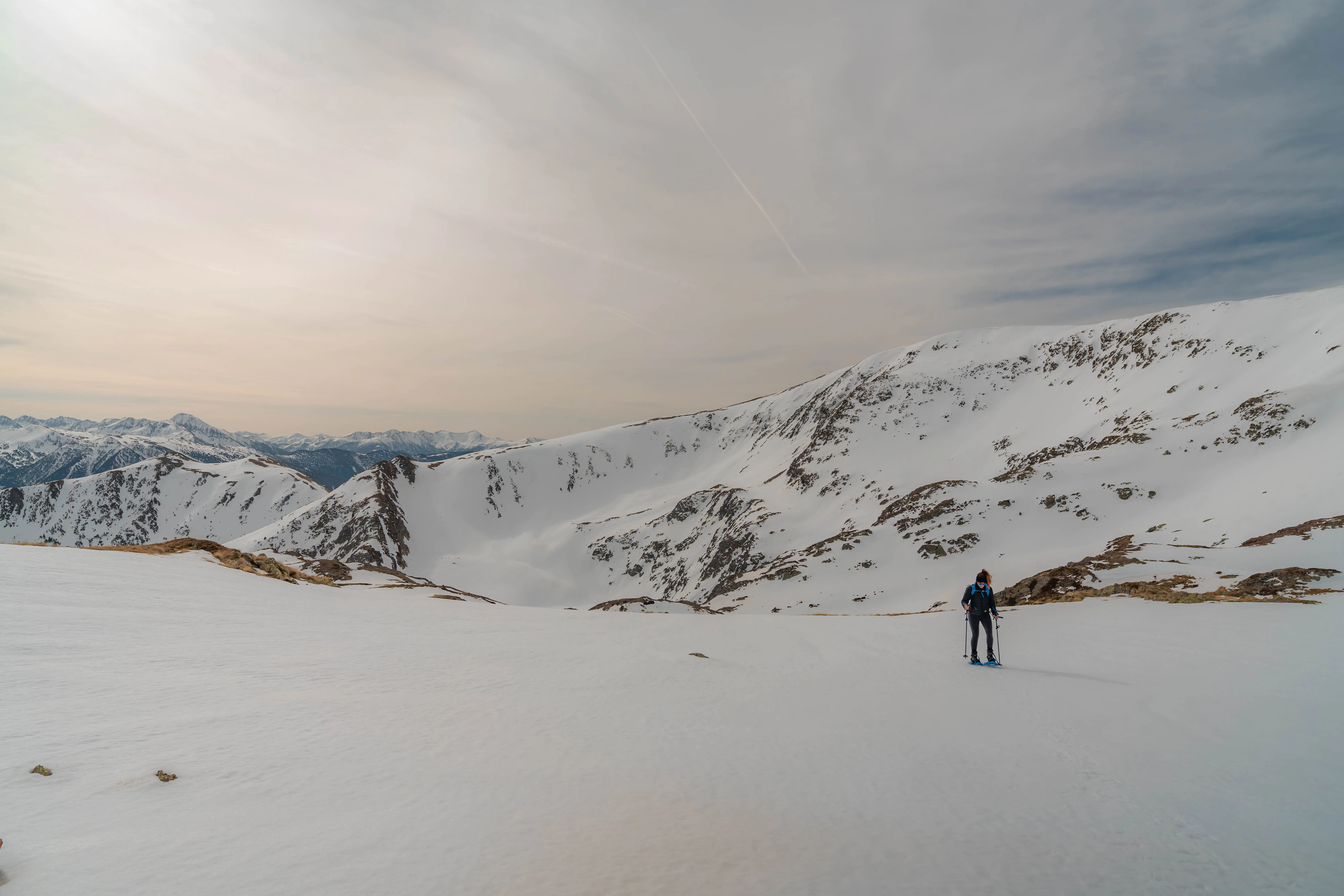 Excursionista con raquetas atravesando un extenso paisaje nevado con cumbres de los Pirineos al fondo durante la ruta al Pic de la Coma del Forn