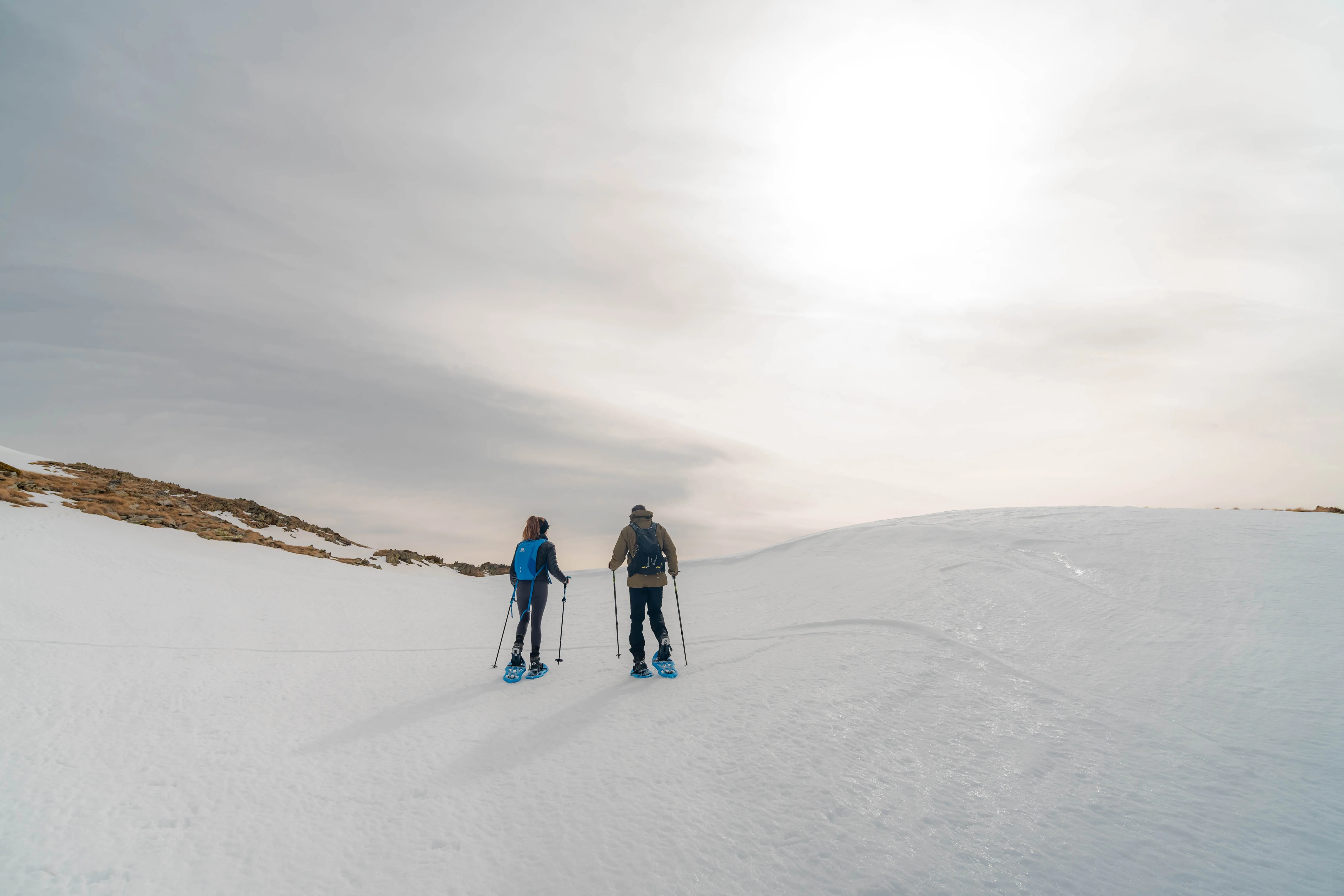 Dos excursionistas con raquetas caminando por una extensión de nieve de alta montaña durante el ascenso al Pic de la Coma del Forn