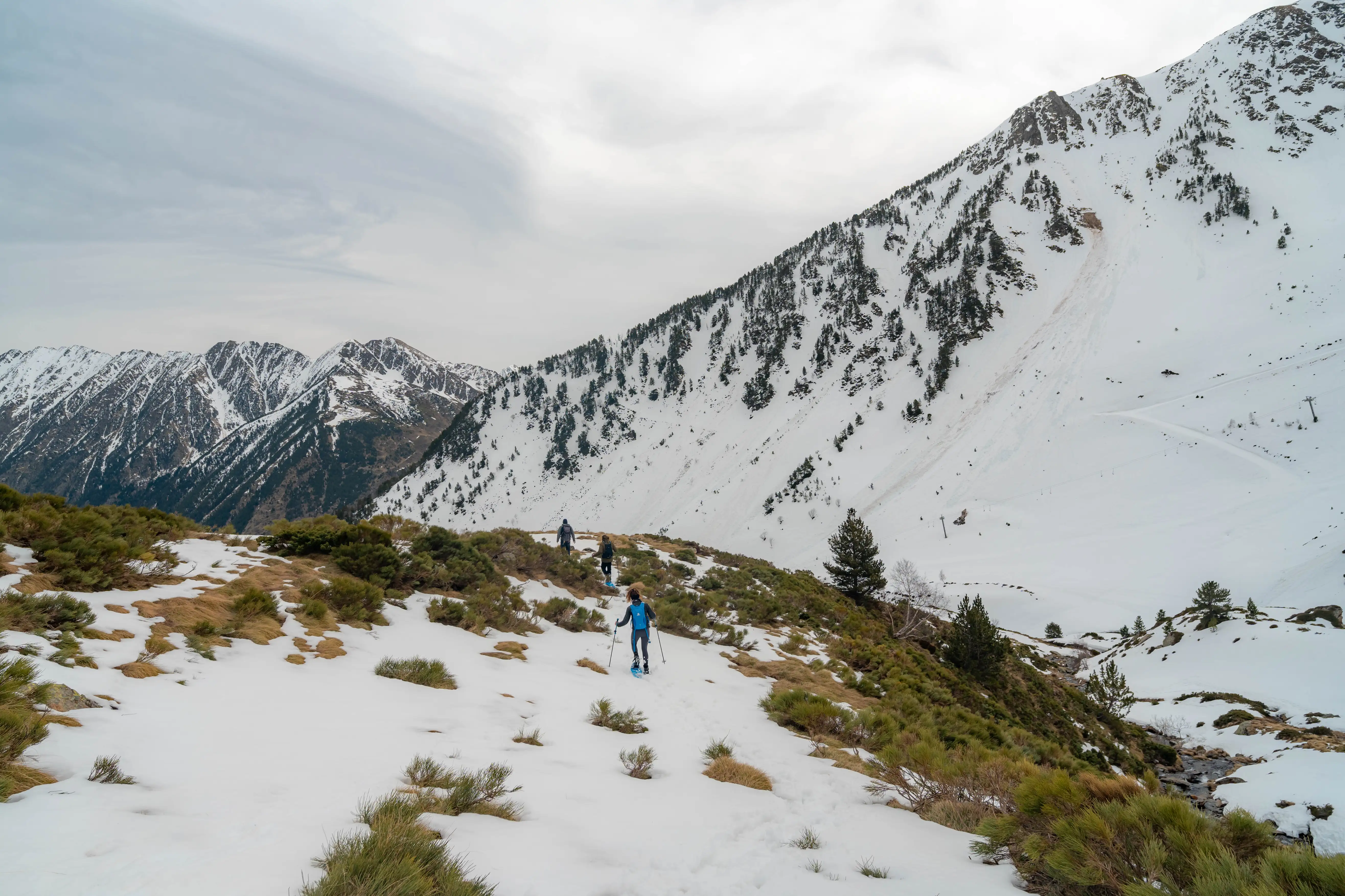 Excursionista con raquetas atravesando un paisaje de alta montaña con cumbres nevadas durante la ruta al Pic de la Coma del Forn