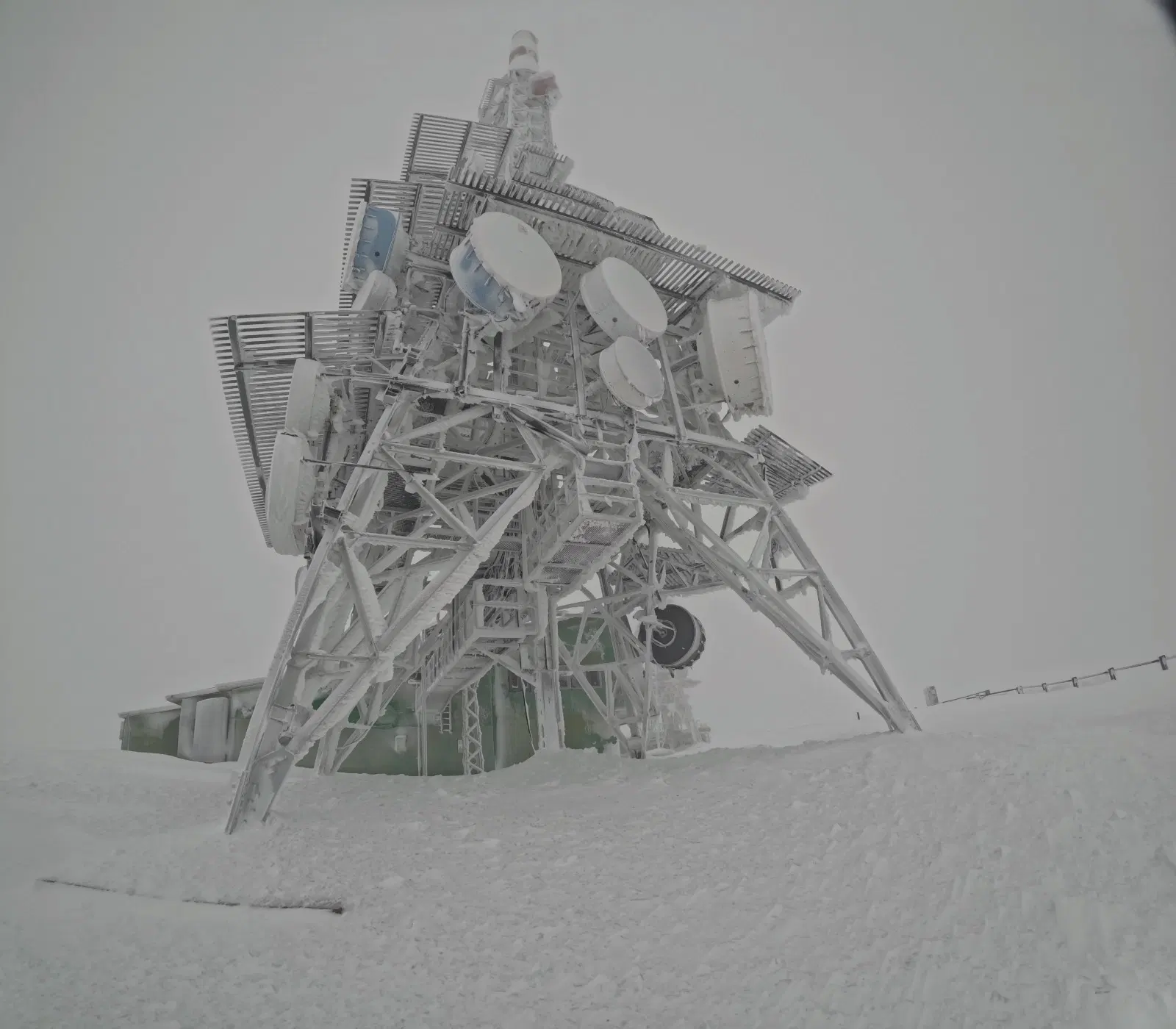 Torre de telecomunicaciones cubierta de hielo y nieve en la cima del Pic de l’Orri durante la ruta con raquetas desde Port Ainé