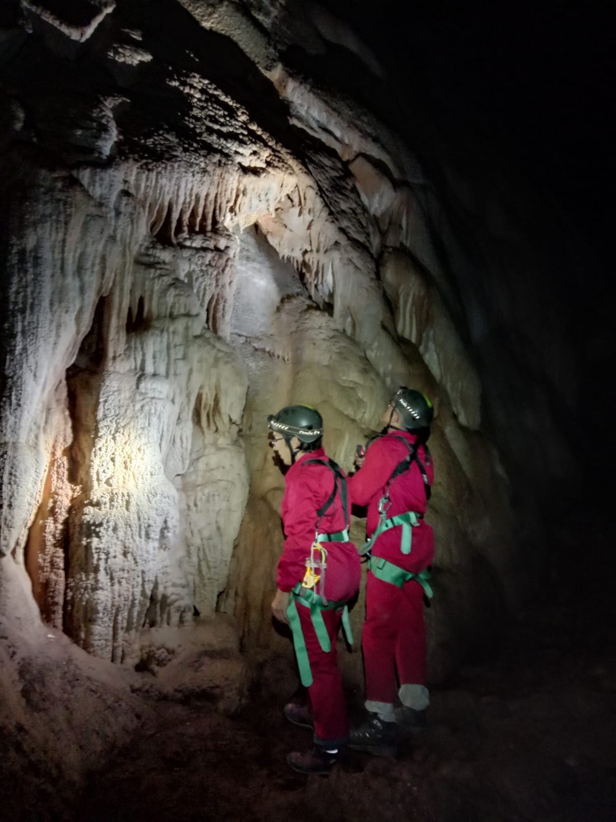 Dos espeleòlegs observant estalactites i colades calcàries a l’interior de la Sima del Barbuxell