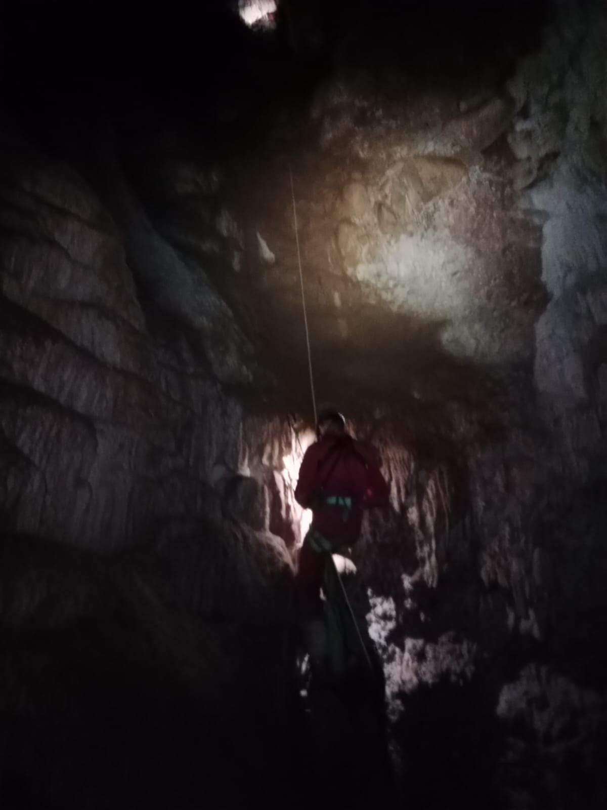Espeleòleg descendint amb corda per un pas vertical fosc a l’interior de la Sima del Barbuxell