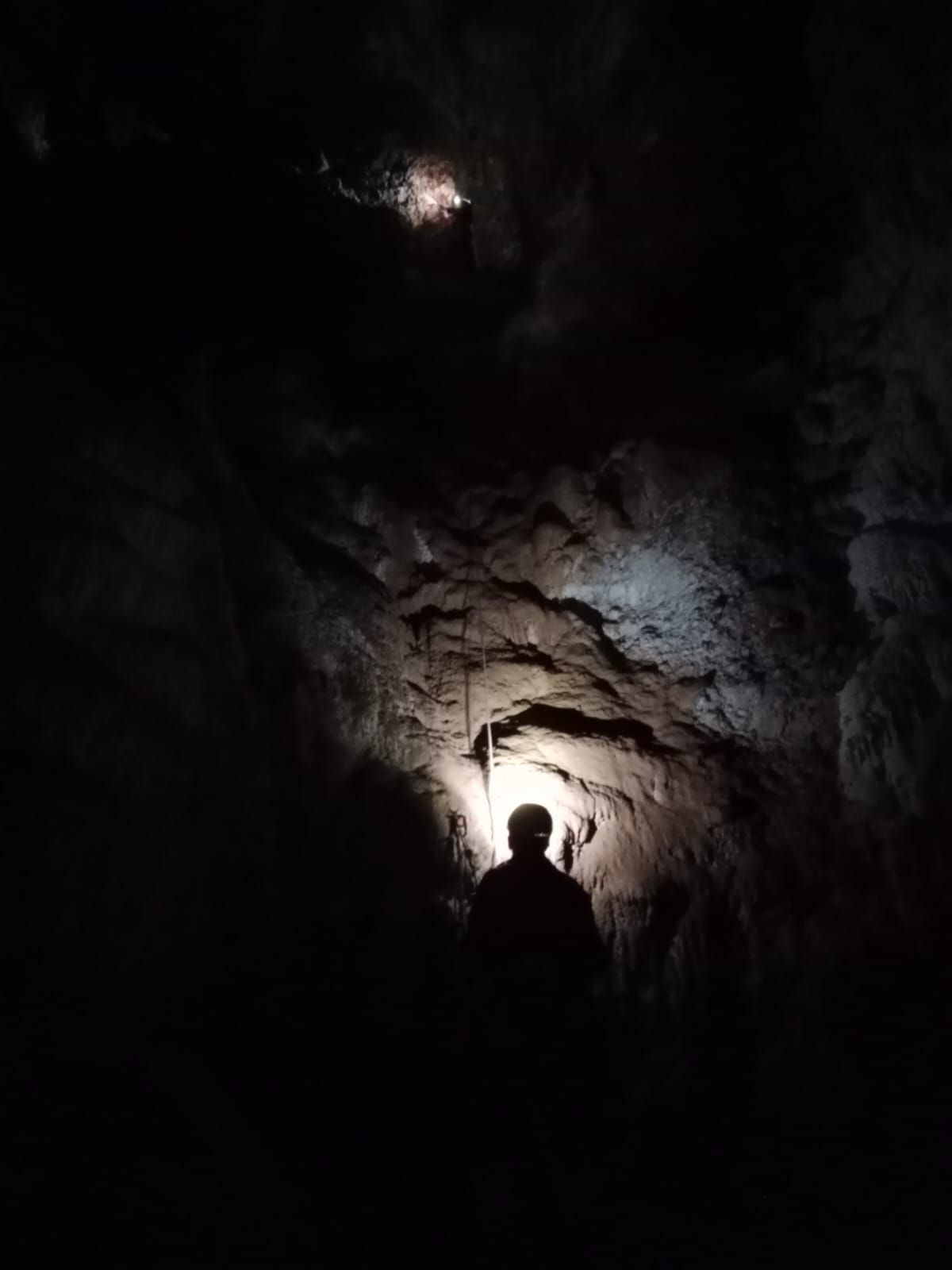 Silueta d’un espeleòleg il·luminada per una llum frontal als passos foscos de la Sima del Barbuxell