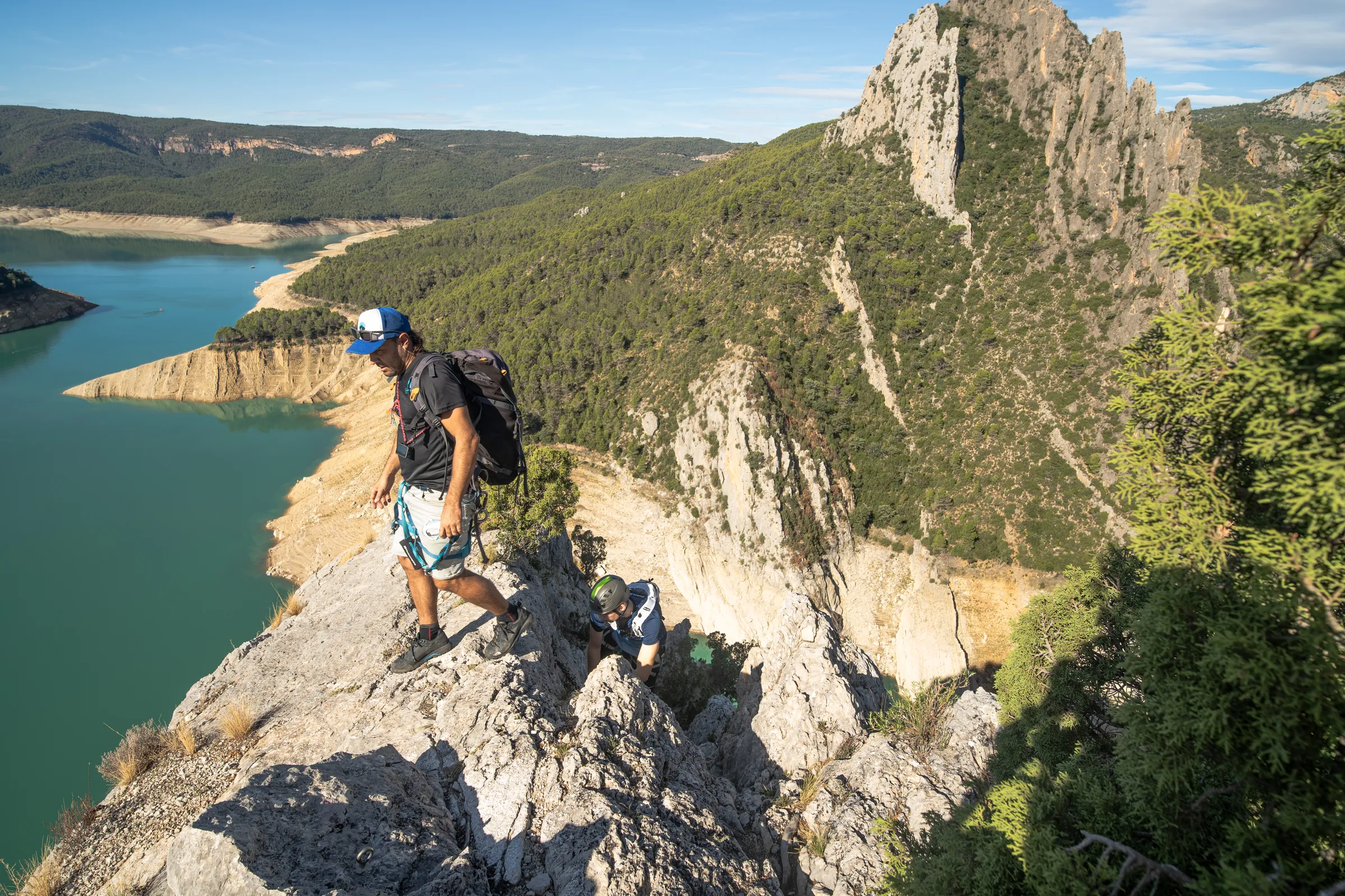 Aventurero caminando por una cresta de la vía ferrata Olmo Soler sobre el embalse