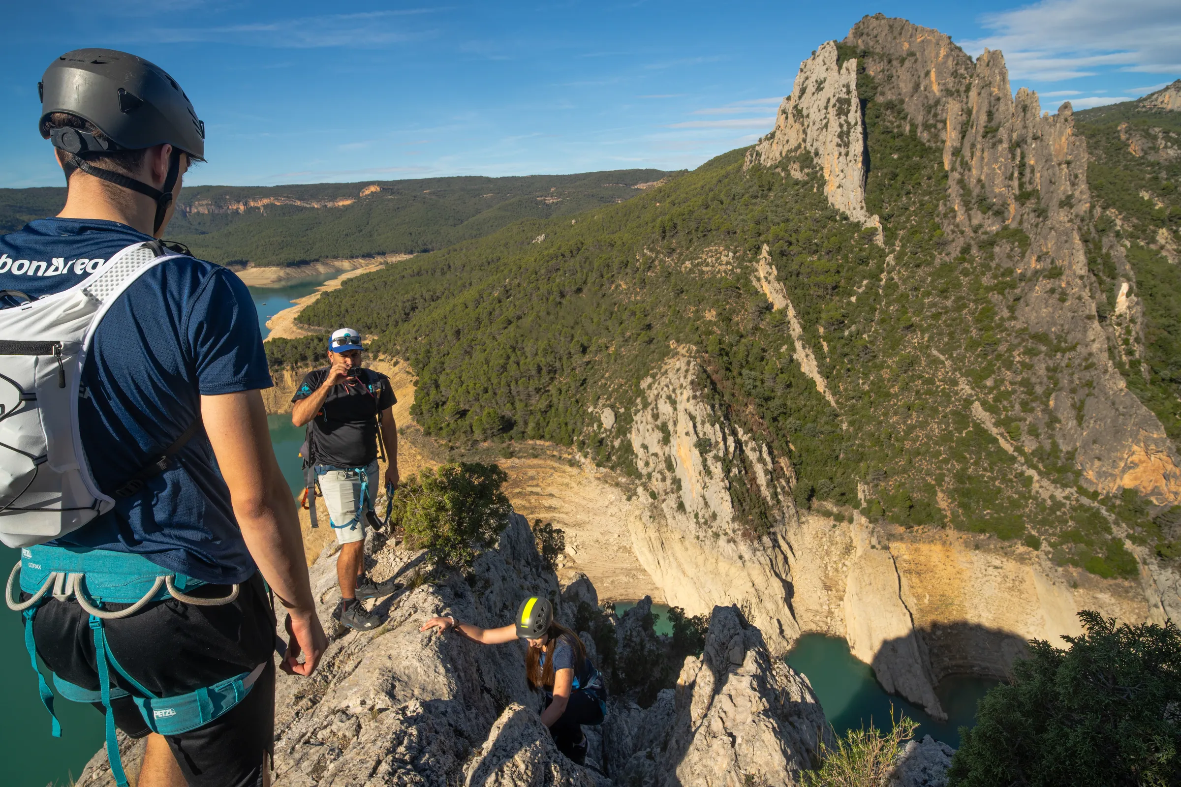 Grupo equipado con casco y arnés en la vía ferrata Olmo Soler frente a las montañas