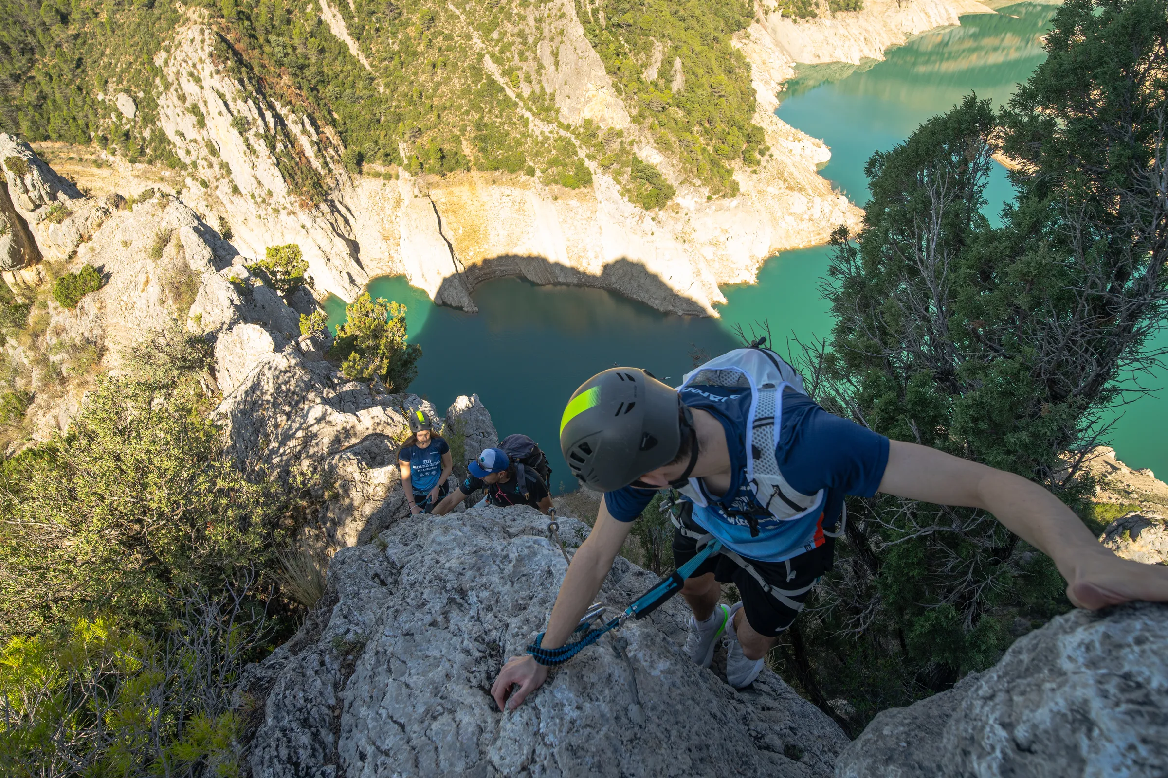 Escalador superando una pared rocosa de la vía ferrata Olmo Soler sobre el embalse