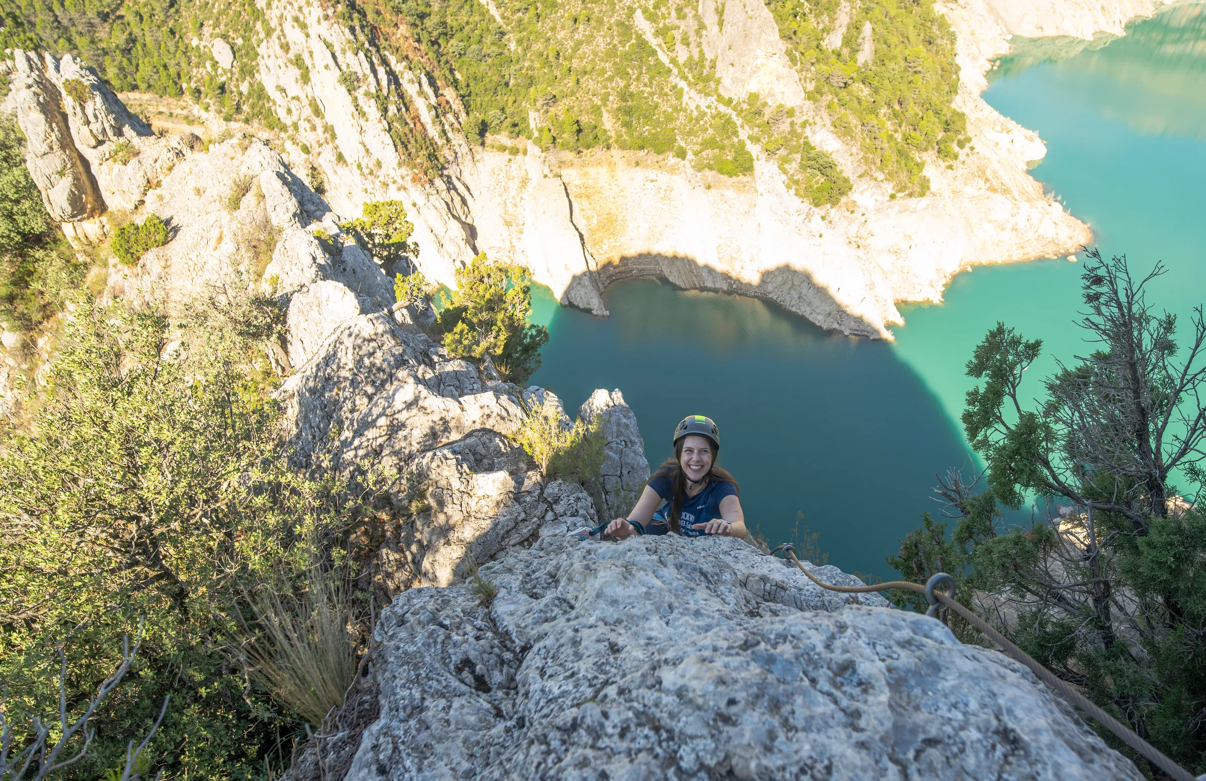 Mujer asomándose desde una pared de roca durante la vía ferrata Olmo Soler