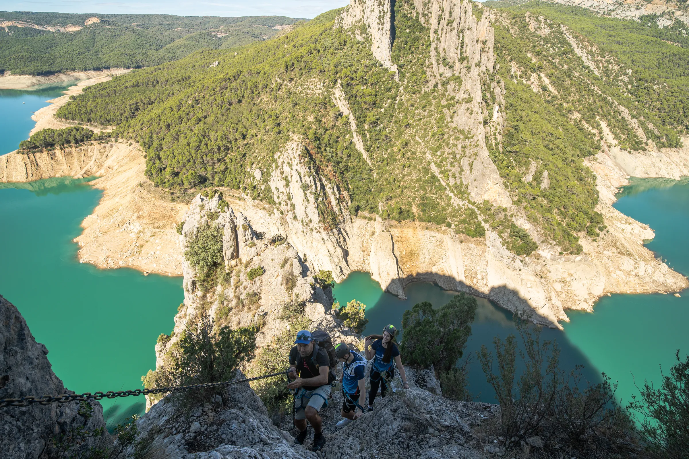 Grupo de escaladores en un tramo expuesto de la vía ferrata Olmo Soler sobre el embalse de Canelles