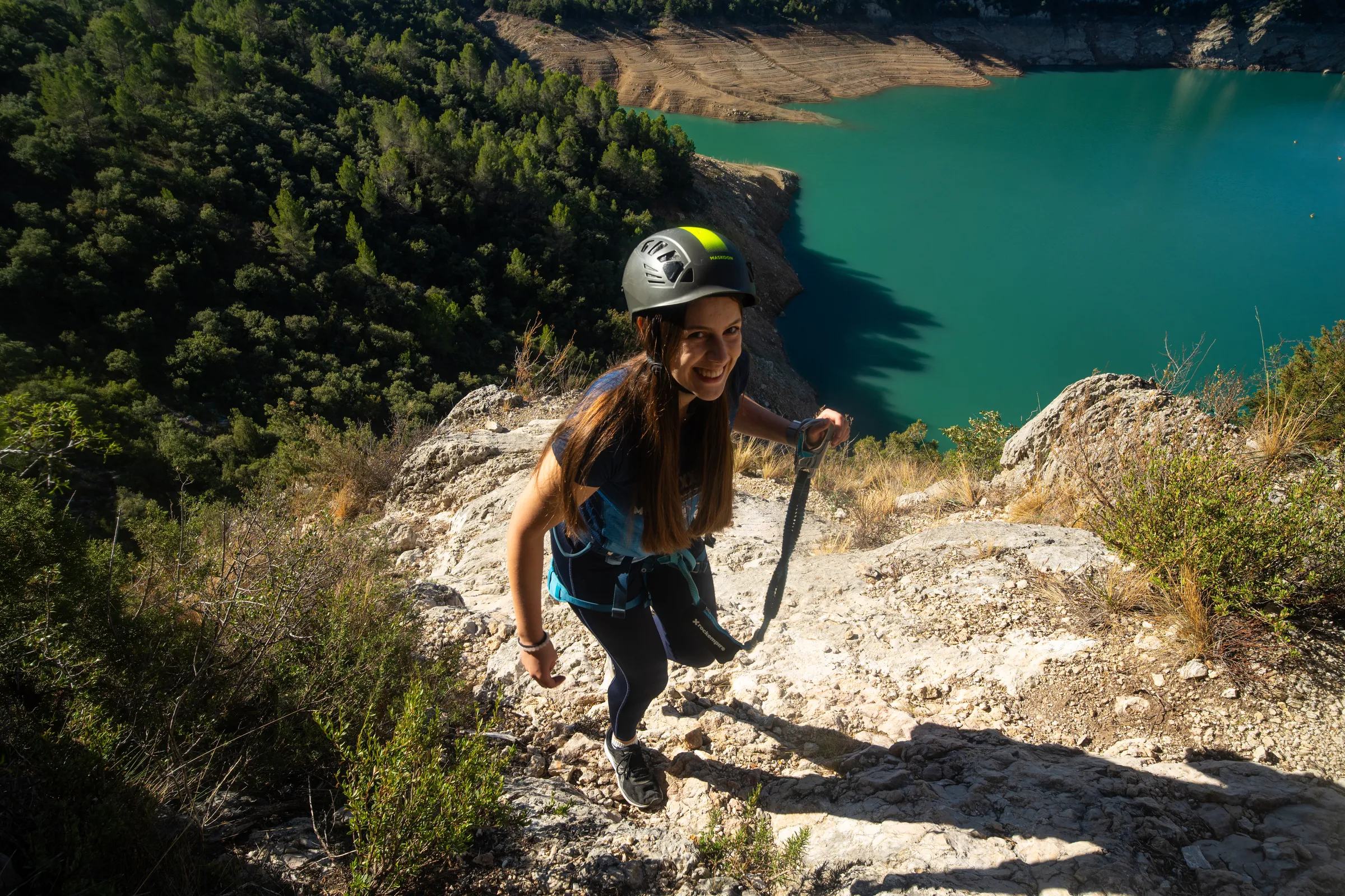 Mujer subiendo por las rocas de la vía ferrata Olmo Soler junto al embalse
